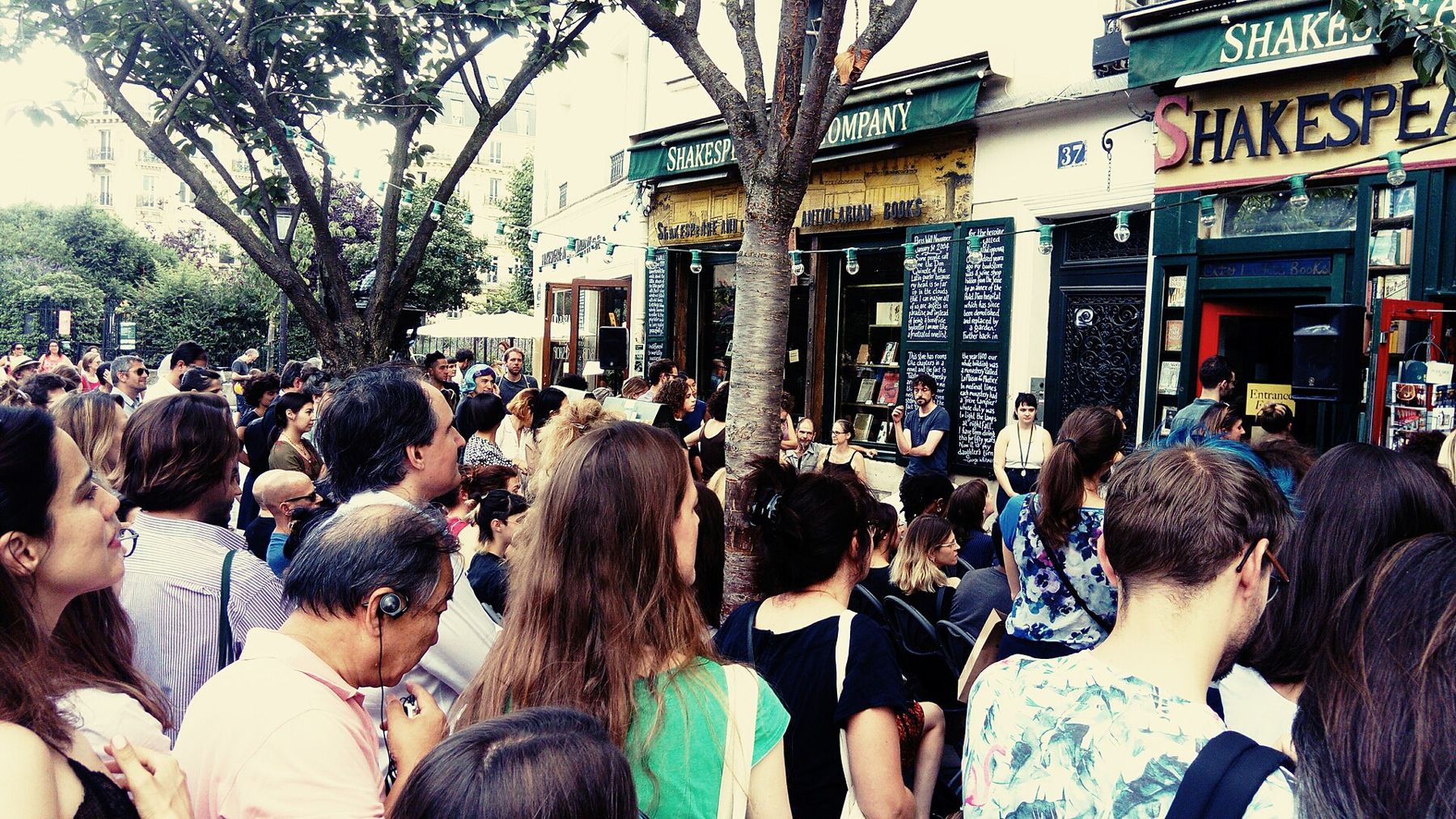 A crowd outside a bookshop listening to a poet